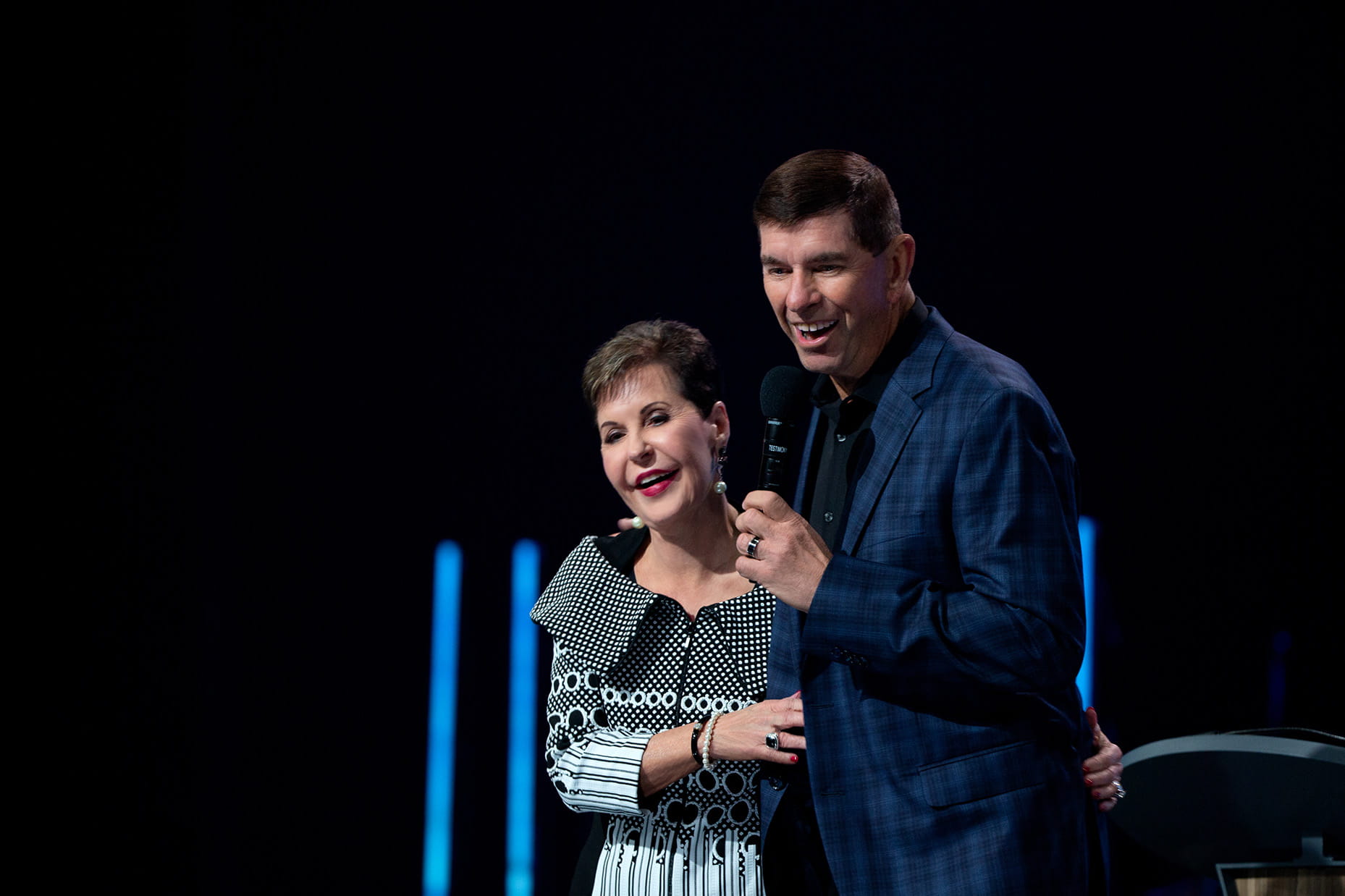 Dave and Joyce Meyer on stage smiling and speaking at a conference